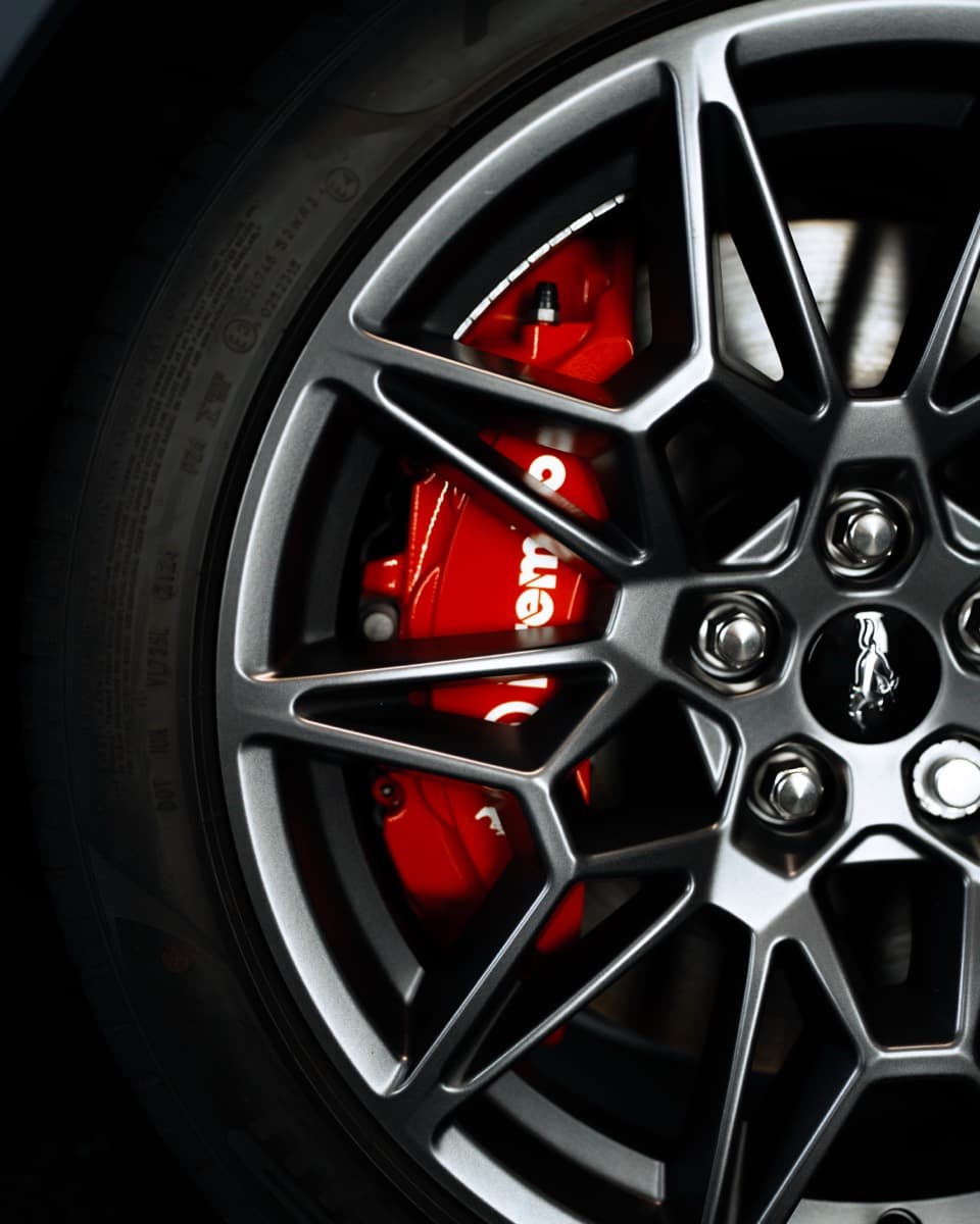 Close-up of the red Brembo brake caliper behind the alloy wheel